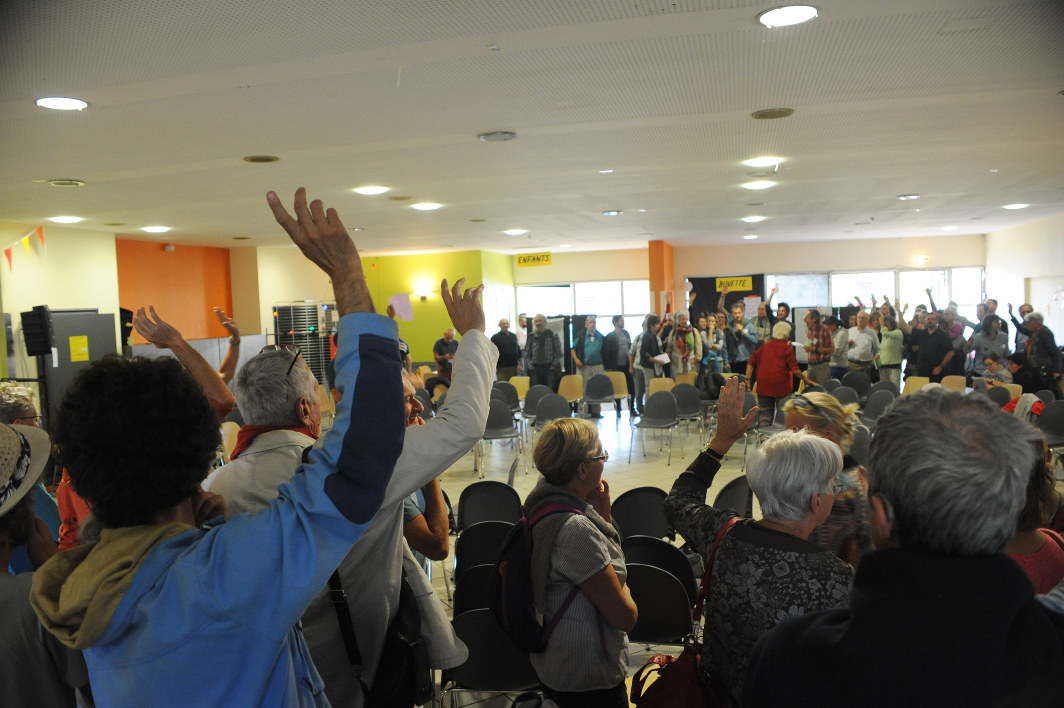 Image d'une assemblée où les personnes lèvent le bras