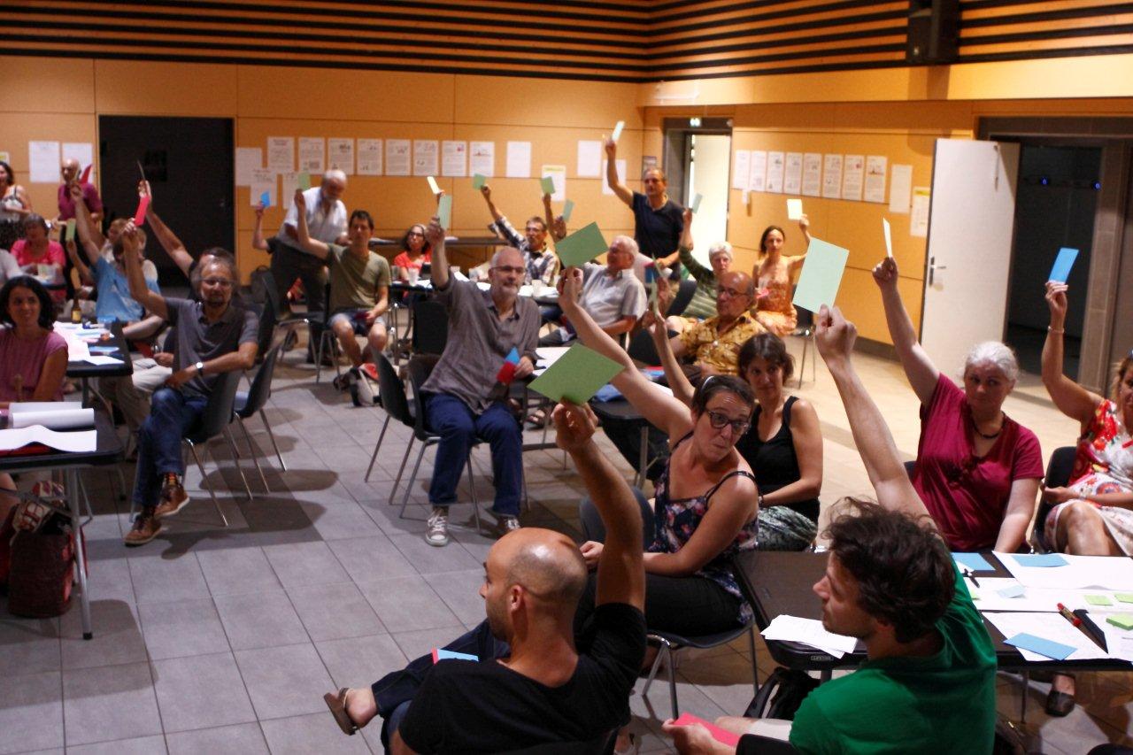 Photo d'une assemblée de citoyen.nes en train de voter