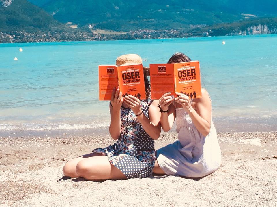 2 groupies de Christian Proust sur la plage d'un lac en train de lire le livre de Christian Proust